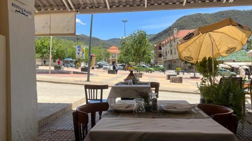 einen Tisch mit gelbem Regenschirm auf einer Straße in der Unterkunft Hotel des cedres,azrou maroc in Azrou