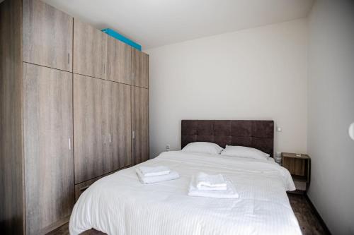 una camera da letto con un grande letto bianco e armadi in legno di John luxury apartment a Alexandroupoli