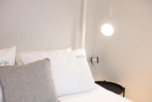 una cama con almohadas blancas y una luz en ella en MeYia studios en Tesalónica
