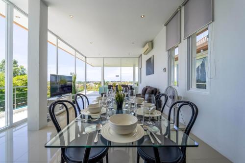 a dining room with a glass table and chairs at Phu Montra Villa with Ocean View in Khao Tao
