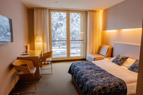 Habitación de hotel con cama, escritorio y ventana en Hotel Thermana Park Laško**** Superior en Laško