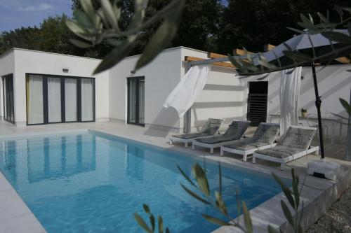 a swimming pool with chairs next to a house at Accomodation TERRAROSSA in Fažana