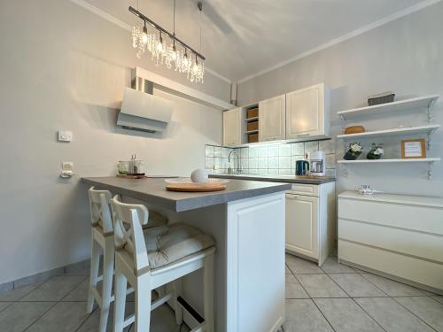 a kitchen with white cabinets and a island with stools at TheasHomly in Kastanéa
