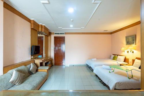 Urbanview Hotel P Residence Asemka في جاكرتا: غرفة فندقية بسريرين واريكة