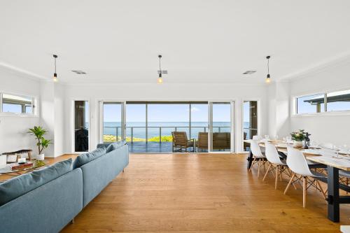 a living room with a long couch and a table at Ochre Sunsets - Moana - C21 SouthCoast Holidays in Moana