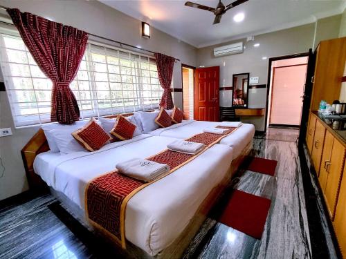a large white bed in a room with windows at Hotel GVS Residency in Yercaud