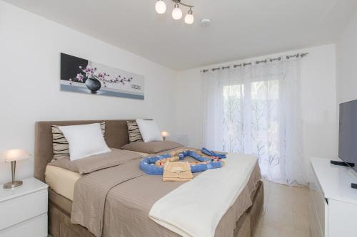 een witte slaapkamer met een groot bed en een raam bij House Zrile with jacuzzi in Baška