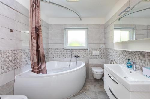 een badkamer met een bad, een toilet en een wastafel bij House Zrile with jacuzzi in Baška