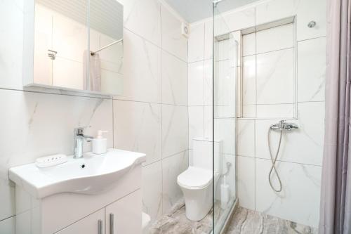 a white bathroom with a sink and a shower at Marika's House in Kallirakhi