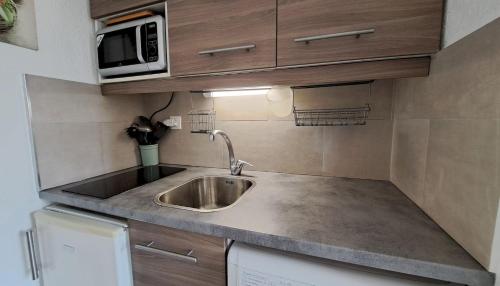 małą kuchnię ze zlewem i kuchenką mikrofalową w obiekcie Studio à 50 m de la plage et du sentier littoral w Hyères
