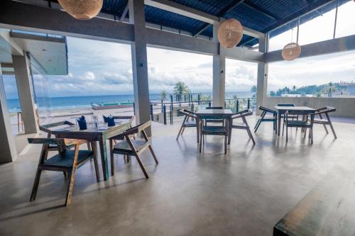 a restaurant with tables and chairs and a view of the ocean at Somerset Mirissa Blue in Mirissa