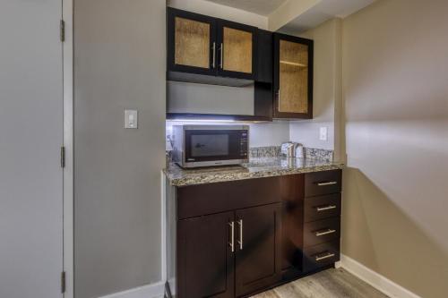 a kitchen with brown cabinets and a microwave at Hotel Weston in Marietta