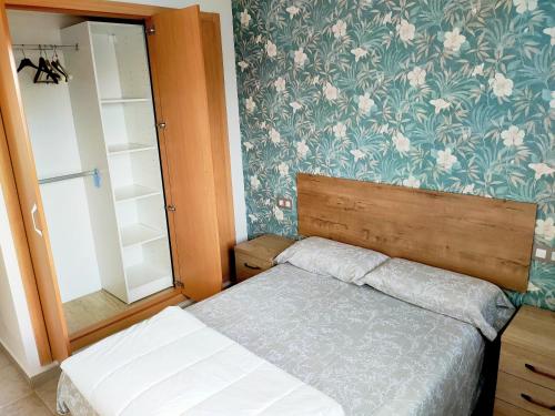 a bedroom with a bed and a flowery wallpaper at Panoramica Golf Karilo in Sant Jordi