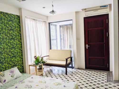 ein Schlafzimmer mit einem Bett, einem Stuhl und einer Tür in der Unterkunft Mika Homestay Friends House in Hanoi