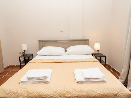 a bed with white towels on it with two tables at ALLAGIANNIS GROUP APARTMENTS in Markopoulo