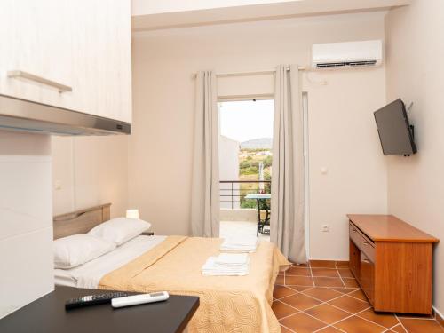 a bedroom with a bed and a tv and a balcony at ALLAGIANNIS GROUP APARTMENTS in Markopoulo