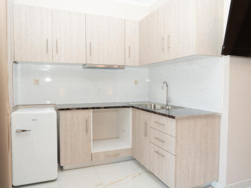 a kitchen with wooden cabinets and a white refrigerator at ALLAGIANNIS GROUP APARTMENTS in Markopoulo
