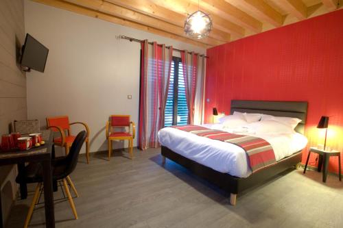 a bedroom with a red wall with a bed and a desk at Ome sweet home in Laubressel