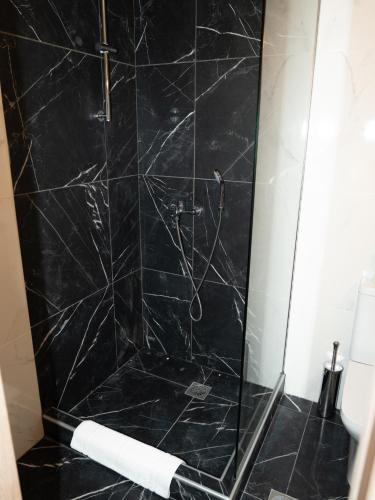 a bathroom with a shower with black marble at ALLAGIANNIS GROUP APARTMENTS in Markopoulo