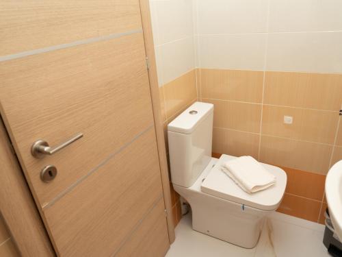 a bathroom with a toilet and a wooden door at ALLAGIANNIS GROUP APARTMENTS in Markopoulo