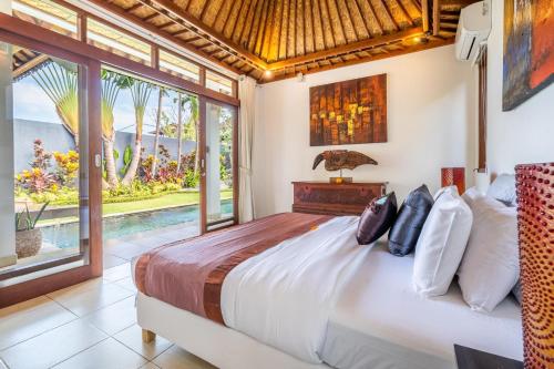 um quarto com uma cama grande e uma janela grande em Romantica Villa Ubud em Ubud