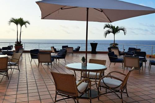 a patio with tables and chairs and an umbrella at Marriott Venezuela Hotel Playa Grande in Playa Grande