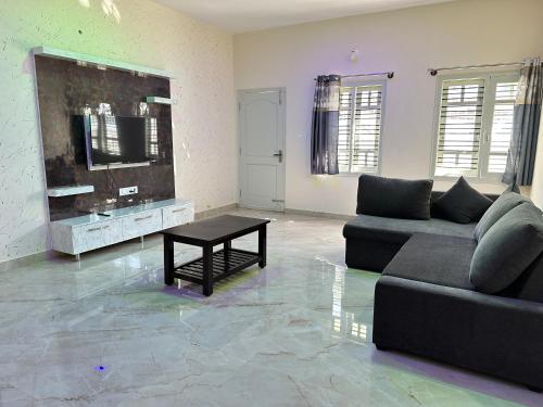 a living room with a couch and a table at Anthara Service Apartment in Belūr