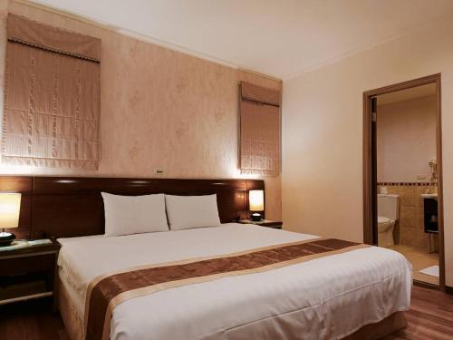 a hotel room with a large bed and a bathroom at 文化信然 in Tainan