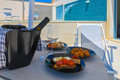 a table with plates of food and a glass of wine at Perle Marine Suite Apartments in Castro di Lecce
