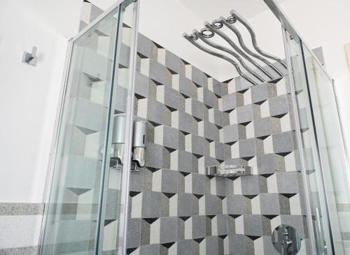 una ducha de cristal con pared a cuadros en Perle Marine Suite Apartments, en Castro di Lecce