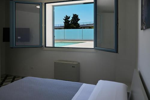 a bedroom with two windows and a view of a pool at Perle Marine Suite Apartments in Castro di Lecce