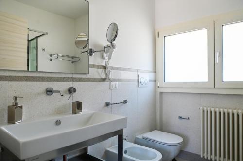 a bathroom with a sink and a toilet and a mirror at Perle Marine Suite Apartments in Castro di Lecce