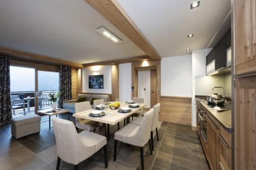 Residence Alpen Lodge في لا روزيير: مطبخ وغرفة طعام مع طاولة وكراسي