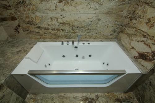 a white bath tub in a stone bathroom at The Ocean Pearl Dharmasthala Ujire in Dharmastala