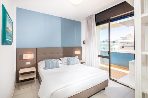 una camera da letto con un letto bianco e una grande finestra di Columbus Vista Mare a Bibione