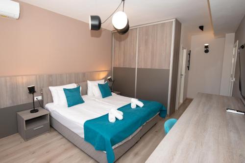 ZARO Apartments في بيتولا: غرفة نوم مع سرير ووسائد زرقاء وبيضاء