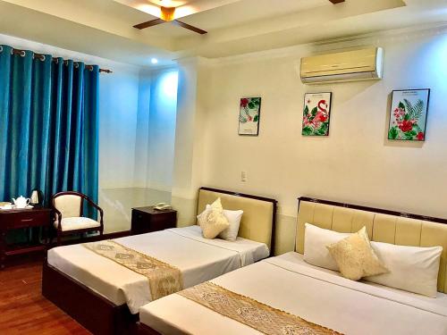 a hotel room with two beds with blue curtains at Linh Phuong 8 Hotel - 24 hours stay in Can Tho