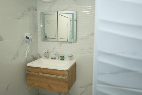 a white bathroom with a sink and a mirror at ZARO Apartments in Bitola