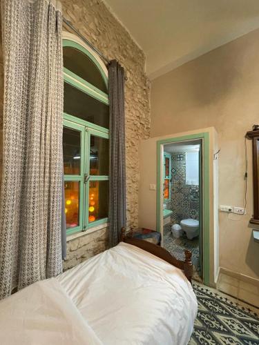a bedroom with a bed and a window and a bathroom at Alf leila wa leila boutique in Haifa