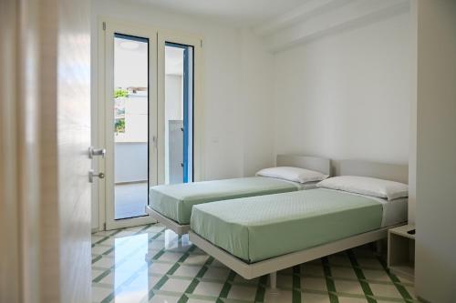 - 2 lits dans une chambre avec fenêtre dans l'établissement Perle Marine Suite Apartments, à Castro di Lecce