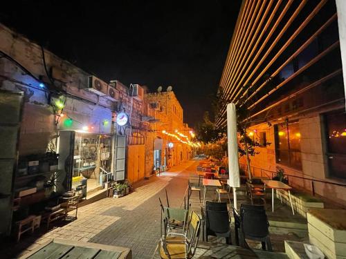 an empty street with tables and chairs at night at Alf leila wa leila boutique in Haifa