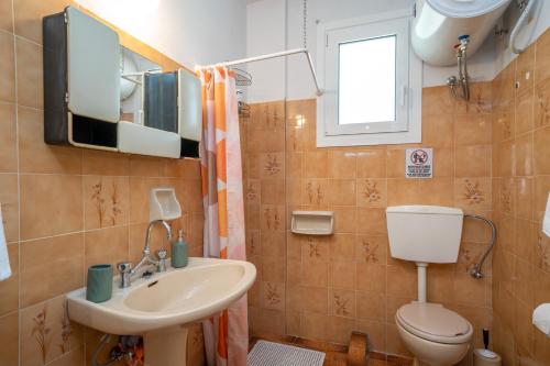ein Badezimmer mit Toilette und Waschbecken in der Unterkunft Artemis House in Karavomylos