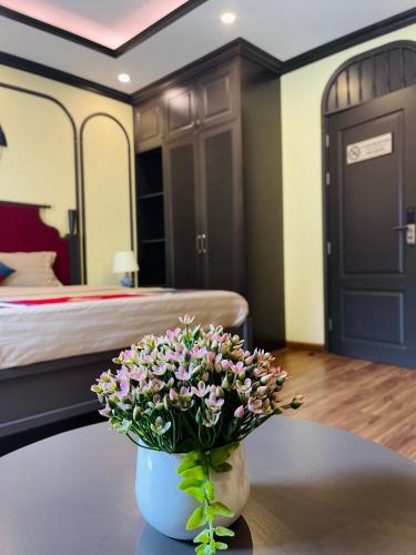 a vase with flowers on a table in a bedroom at Moonlight Hotel Sa Pa in Sa Pa
