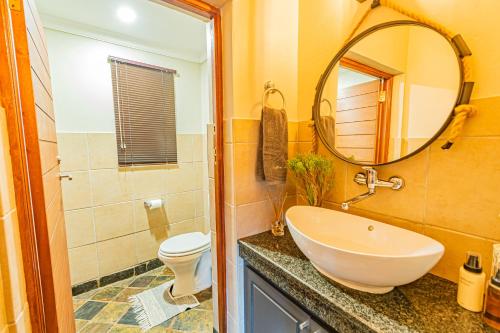 a bathroom with a sink and a toilet and a mirror at Kubu Lodge in Mabula