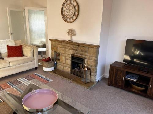 un soggiorno con camino e TV di Charming 4-Bed House in Cheltenham Free Parking a Cheltenham