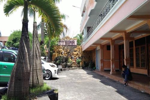een palmboom en een auto geparkeerd voor een gebouw bij Hotel Bima in Klaten