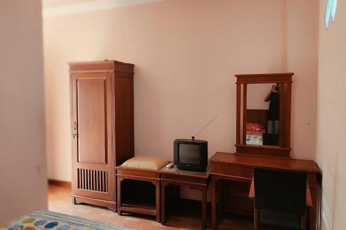 een kamer met een bureau, een televisie en een spiegel bij Hotel Bima in Klaten