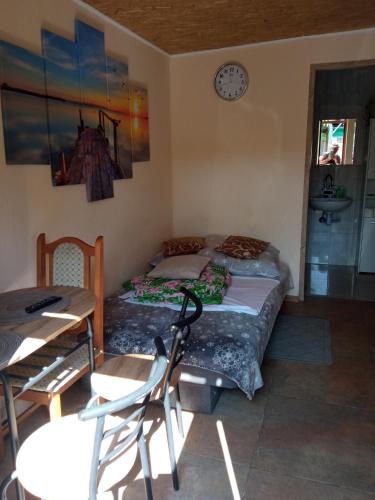 1 dormitorio con cama, mesa y reloj en Domek letni, en Pozezdrze