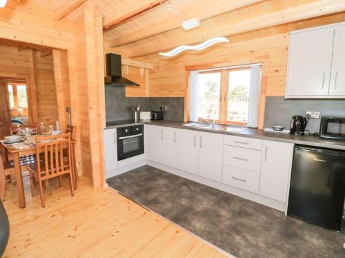 a kitchen with white cabinets and a wooden ceiling at Ty Will, Parc Y Fronwen in Newborough