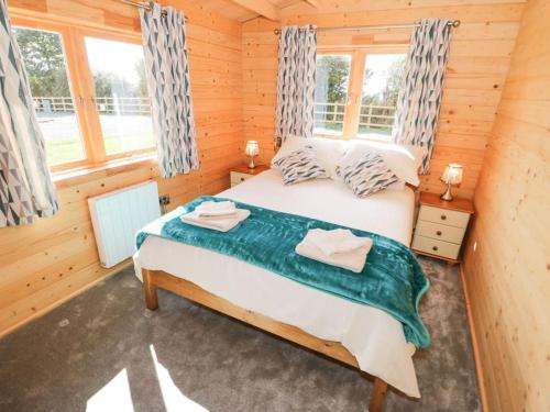 a bedroom with a bed in a wooden cabin at Ty Will, Parc Y Fronwen in Newborough